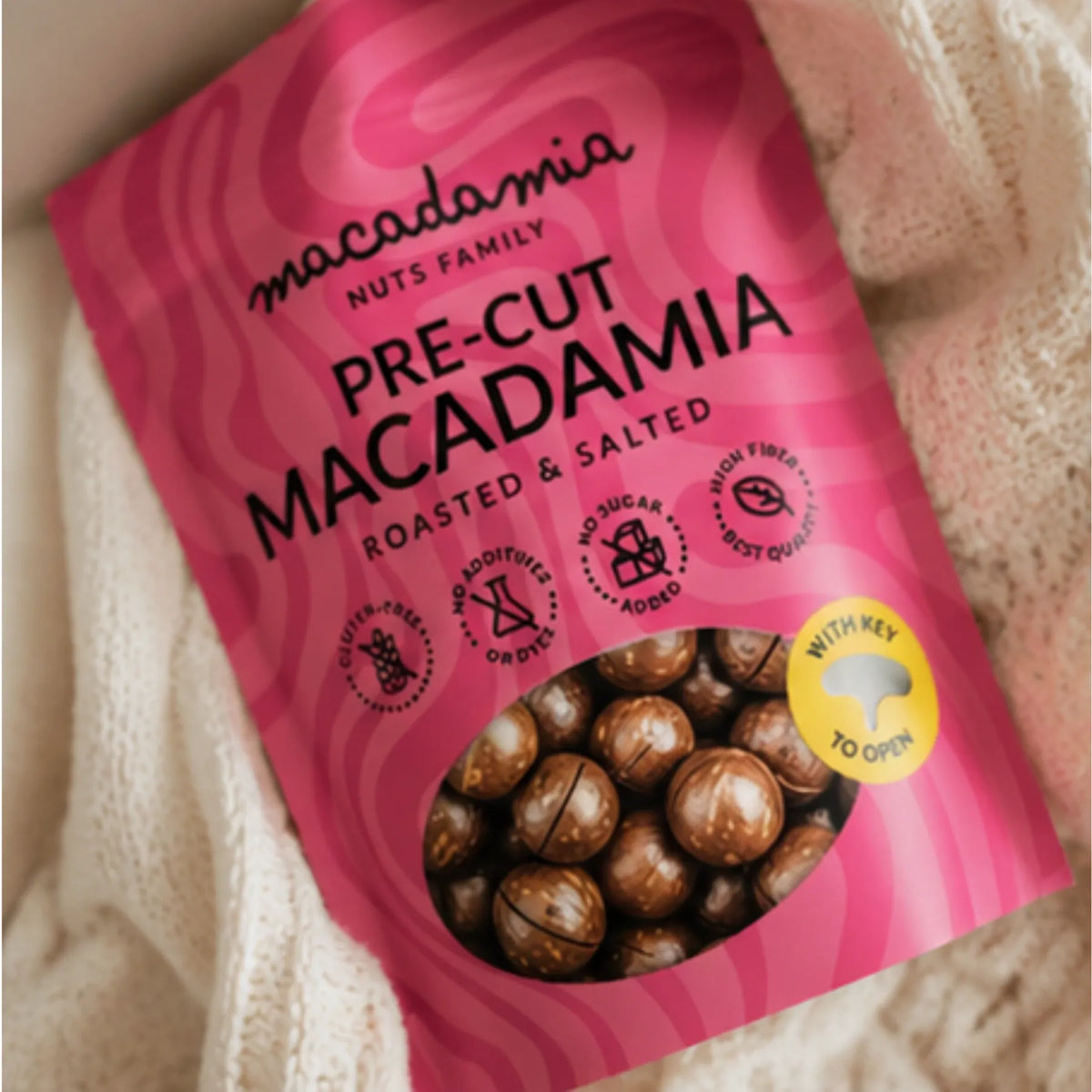 Rosa Verpackung mit gerösteten gesalzenen Macadamianüssen in Schale
