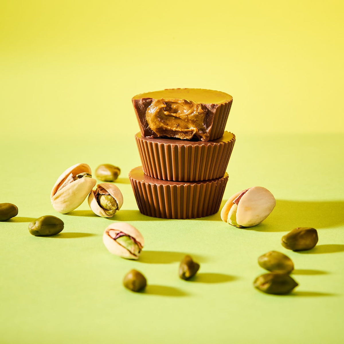Bio Pistazienbutter Cups Salted Pistachio gestapelt mit Pistazienkernen und Schalen