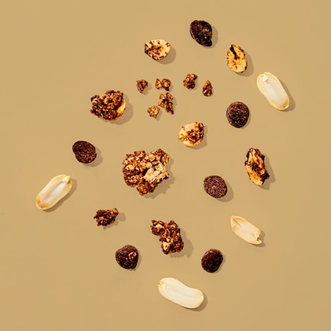 Bio Erdnuss Granola Schoko mit Erdnüssen, Schokostückchen und Granola-Clustern auf beigem Hintergrund