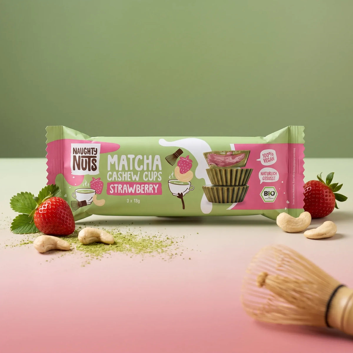 Naughty Nuts Matcha Cashew Cups Erdbeere Verpackung mit Erdbeeren, Cashews und Matcha-Pulver